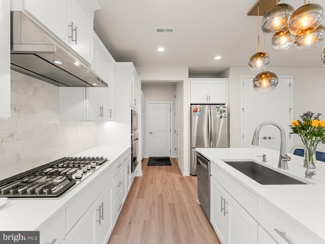 kitchen with light hardwood / wood-style flooring, decorative light fixtures, stainless steel appliances, white cabinetry, and sink