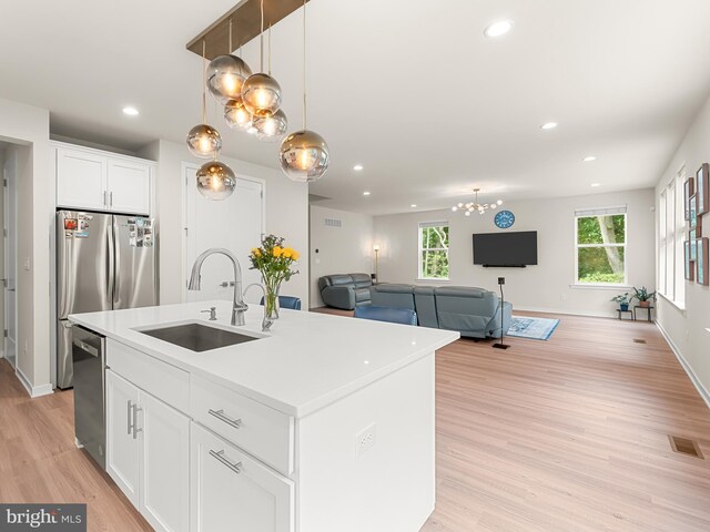 kitchen featuring a center island with sink, light hardwood / wood-style flooring, appliances with stainless steel finishes, sink, and white cabinets