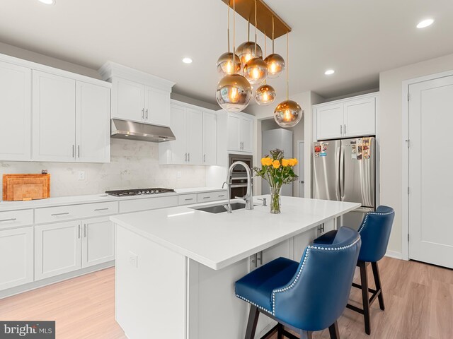 kitchen with a center island with sink, light hardwood / wood-style flooring, sink, and white cabinets