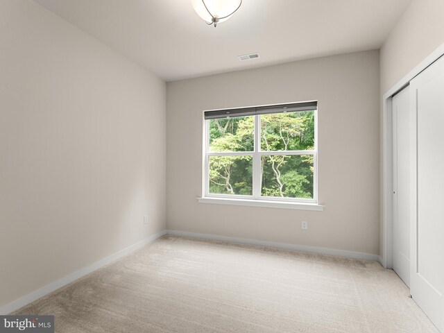 unfurnished bedroom featuring a closet and light colored carpet