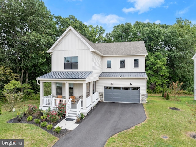 modern farmhouse with stone siding, covered porch, an attached garage, and a standing seam roof