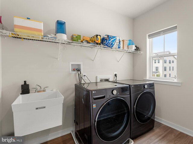 laundry room featuring wood-type flooring, washer and clothes dryer, and sink