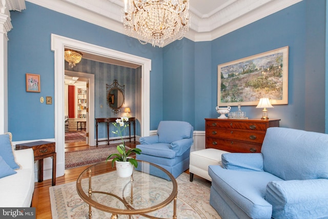 living area with ornamental molding, wood finished floors, and an inviting chandelier