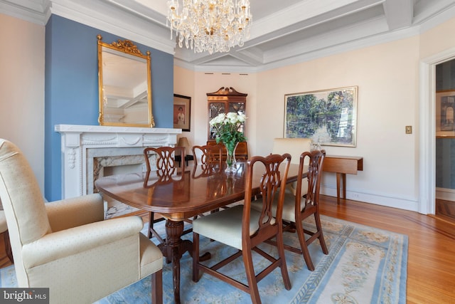 dining room with coffered ceiling, beamed ceiling, a fireplace, wood-type flooring, and ornamental molding