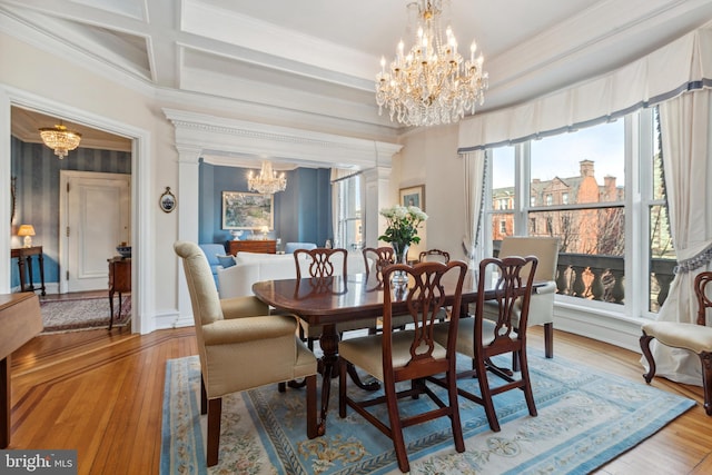 dining space featuring ornamental molding, coffered ceiling, a notable chandelier, and light wood-style flooring