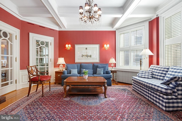 living area with coffered ceiling, wood finished floors, ornamental molding, beam ceiling, and radiator heating unit