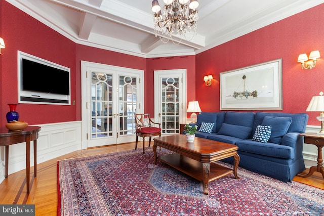 living area featuring a notable chandelier, a wainscoted wall, coffered ceiling, wood finished floors, and beam ceiling