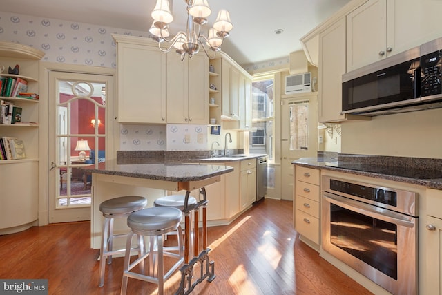 kitchen featuring light wood-type flooring, appliances with stainless steel finishes, a kitchen breakfast bar, and plenty of natural light