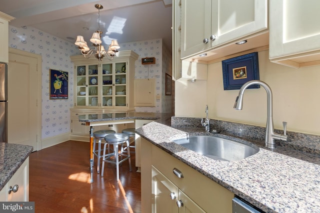 kitchen featuring dark wood-type flooring, an inviting chandelier, stone countertops, and sink