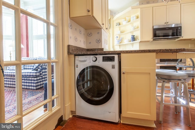 laundry area with wood finished floors, washer / clothes dryer, wallpapered walls, and laundry area