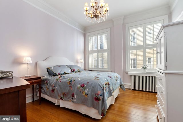 bedroom with light wood-type flooring, an inviting chandelier, radiator, and crown molding