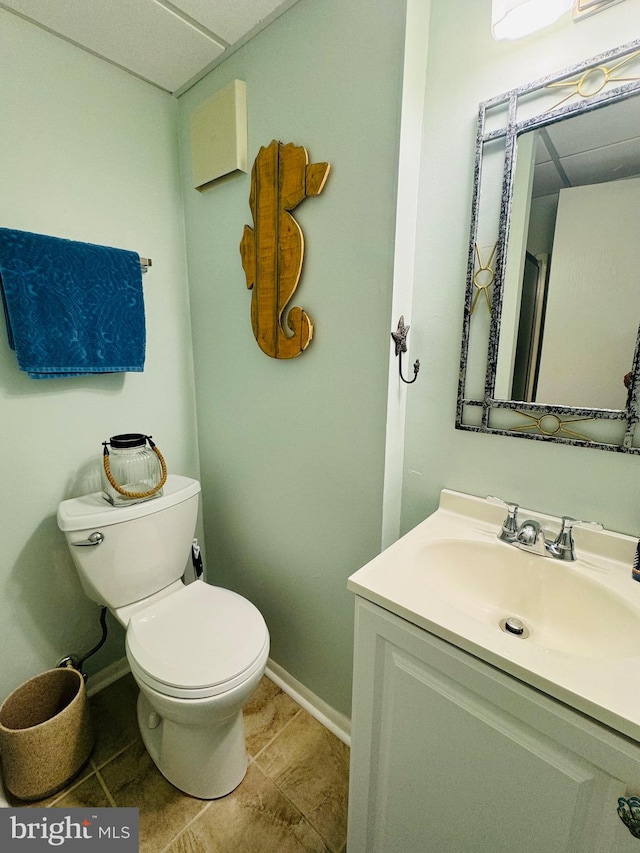 half bathroom featuring baseboards, vanity, and toilet