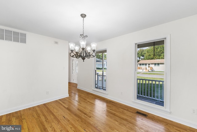 unfurnished dining area featuring hardwood / wood-style floors and a notable chandelier