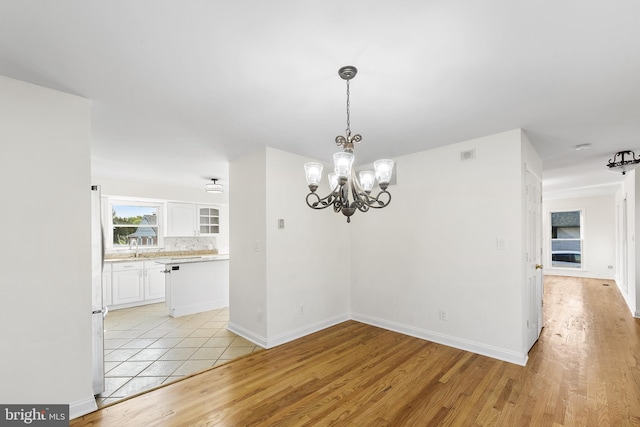 unfurnished dining area with light hardwood / wood-style floors and an inviting chandelier