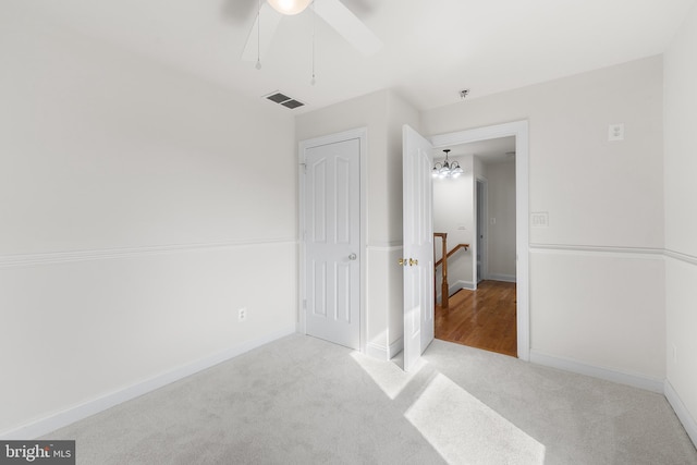 bedroom featuring light colored carpet and ceiling fan with notable chandelier