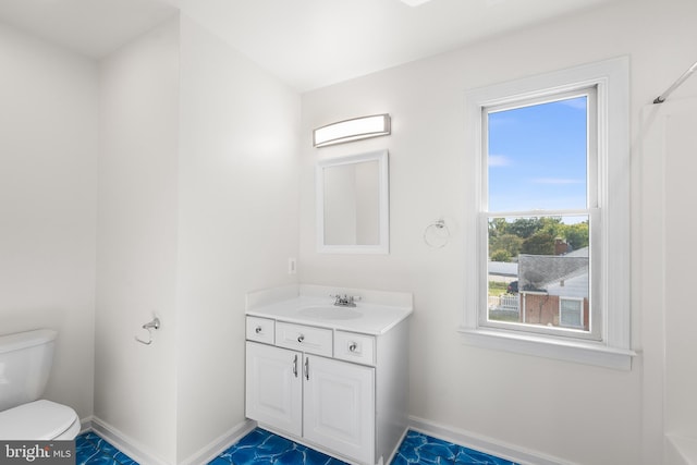 bathroom with plenty of natural light, toilet, and vanity