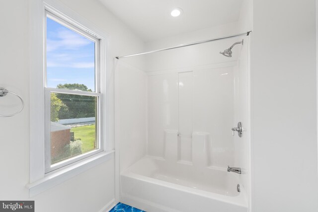 clothes washing area with stacked washer / dryer, a wealth of natural light, and light tile patterned floors