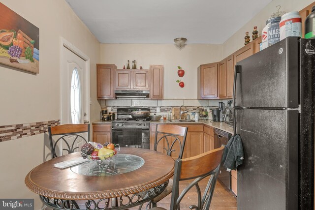 kitchen with black appliances, sink, tasteful backsplash, and light hardwood / wood-style flooring