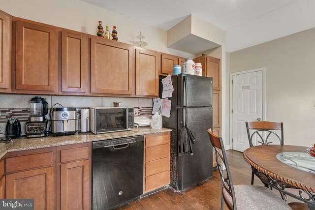 kitchen featuring black appliances, light stone counters, decorative backsplash, and dark hardwood / wood-style flooring