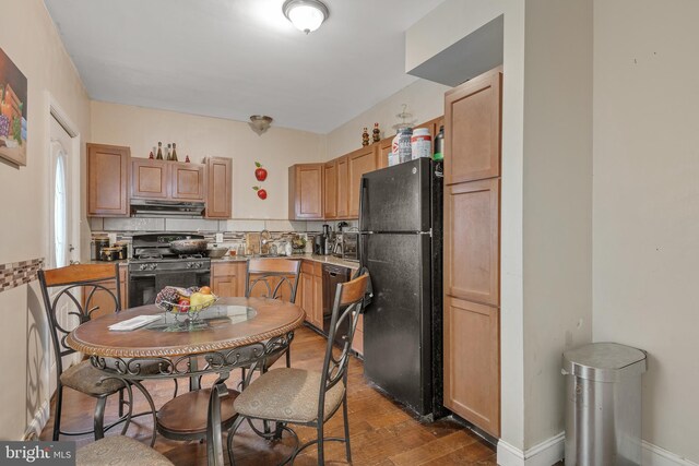 kitchen with backsplash, sink, black appliances, dark hardwood / wood-style floors, and exhaust hood