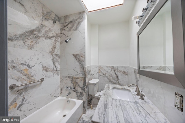 full bathroom with tiled shower / bath combo, vanity, toilet, and tile walls