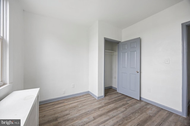 unfurnished bedroom featuring a closet, wood finished floors, and baseboards