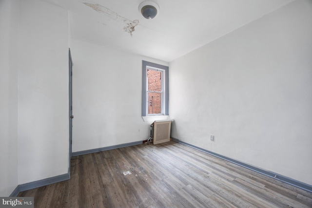 unfurnished room featuring radiator heating unit, wood finished floors, and baseboards