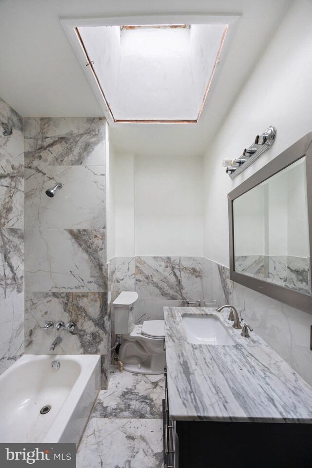 bathroom with vanity, toilet, a skylight, and tile walls