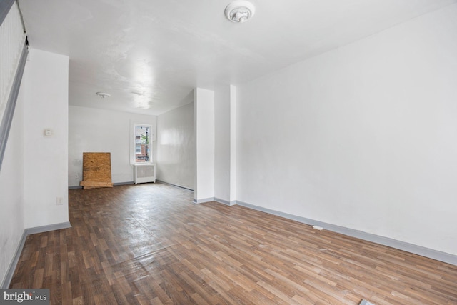 spare room with baseboards and wood finished floors