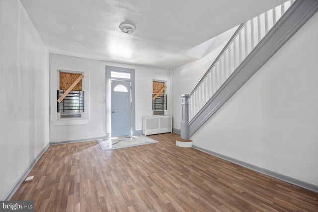 entryway featuring baseboards, stairway, wood finished floors, and radiator