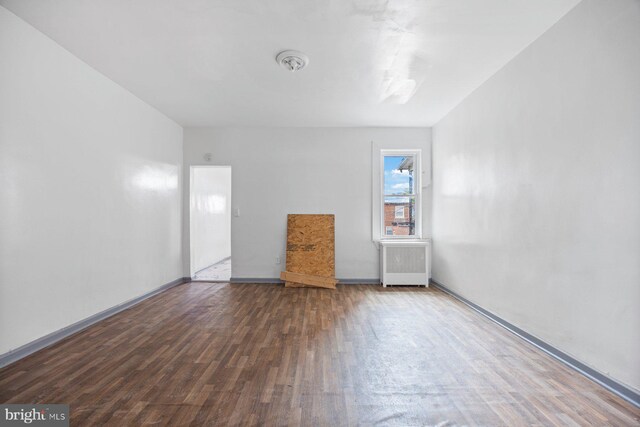 unfurnished bedroom featuring dark hardwood / wood-style floors and radiator heating unit