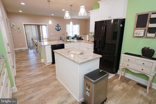 kitchen featuring black appliances, kitchen peninsula, light wood-type flooring, and hanging light fixtures