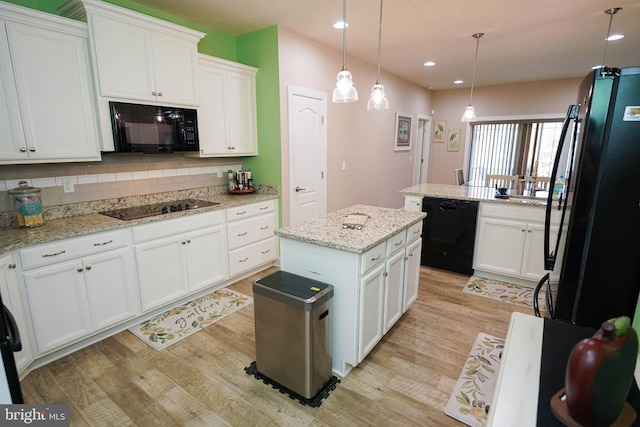 kitchen featuring decorative light fixtures, black appliances, light hardwood / wood-style flooring, a center island, and white cabinetry