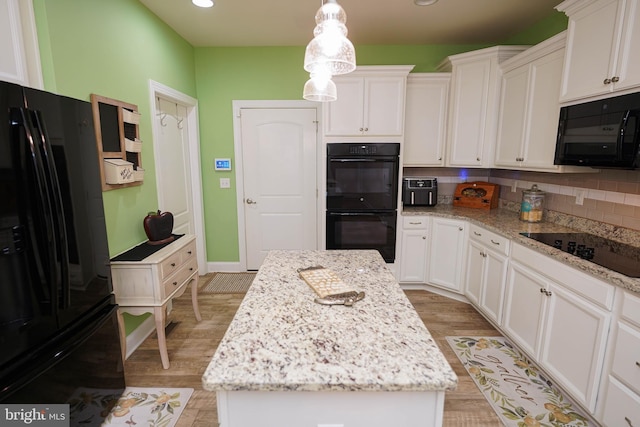 kitchen with light wood-type flooring, backsplash, black appliances, a center island, and white cabinets