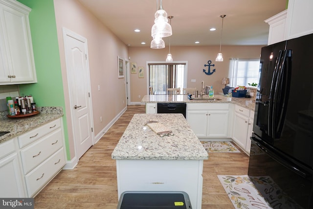 kitchen featuring decorative light fixtures, black appliances, a center island, sink, and white cabinets