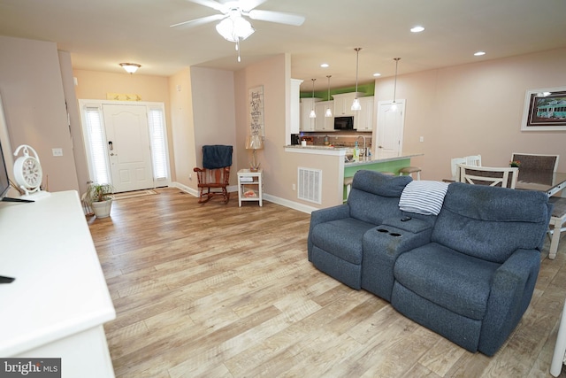 living room featuring ceiling fan and light hardwood / wood-style flooring