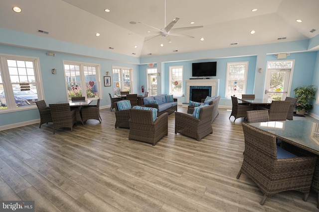 living room with high vaulted ceiling, plenty of natural light, ceiling fan, and light hardwood / wood-style floors