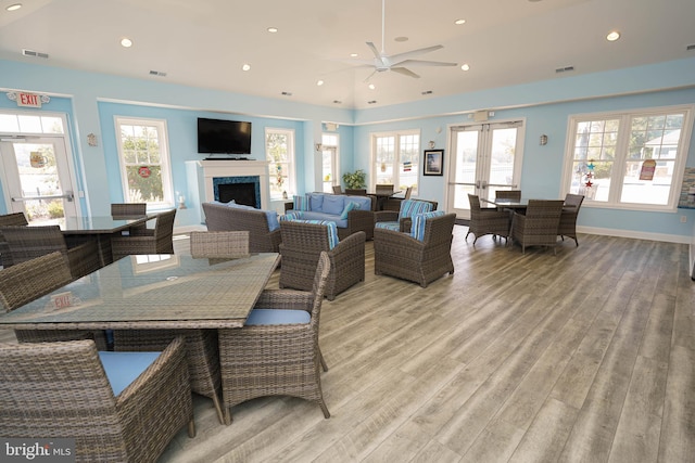 dining area featuring a premium fireplace, ceiling fan, french doors, and light hardwood / wood-style floors