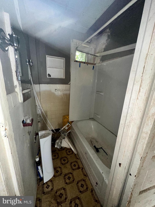 full bathroom featuring washtub / shower combination and tile walls