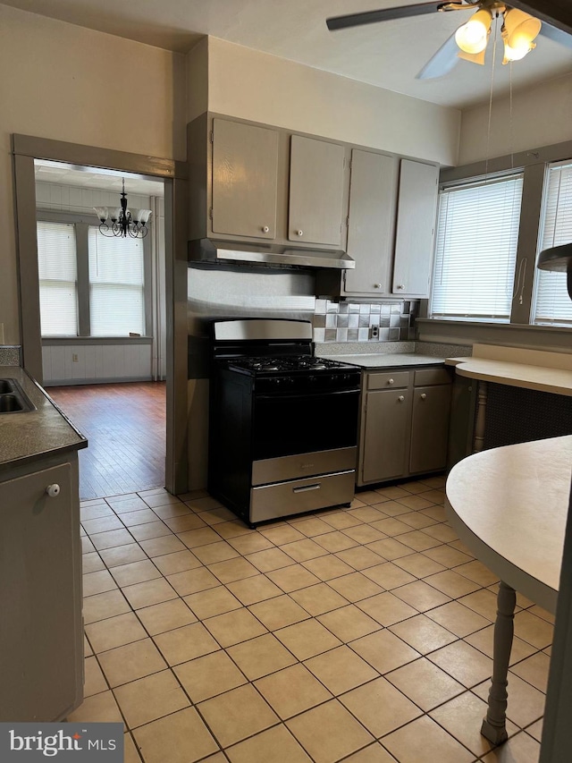 kitchen featuring ceiling fan with notable chandelier, stainless steel range with gas stovetop, light hardwood / wood-style floors, and a healthy amount of sunlight