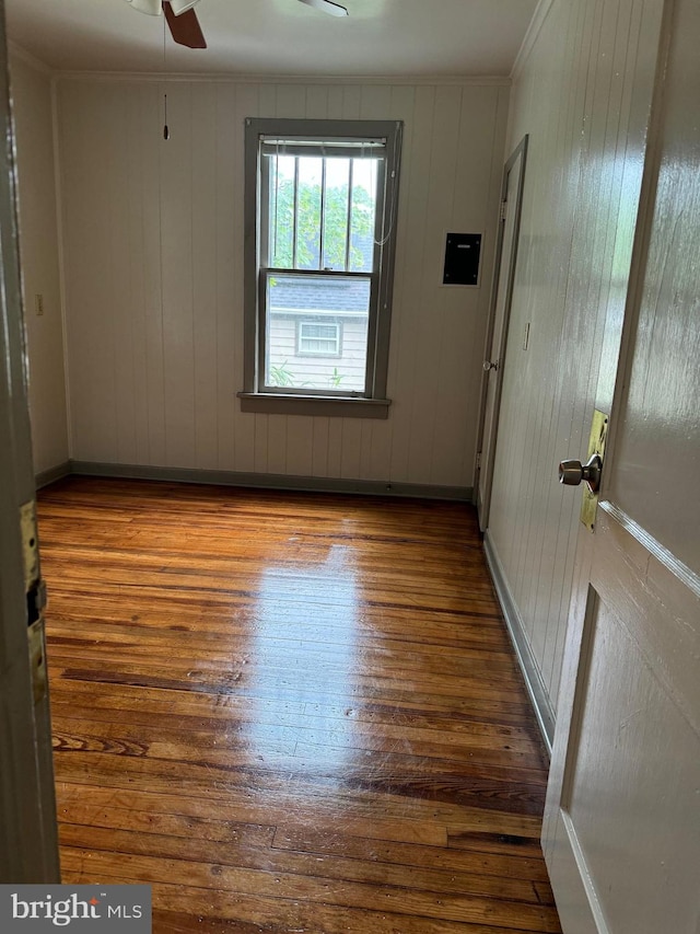 unfurnished room featuring ceiling fan, hardwood / wood-style floors, and wooden walls