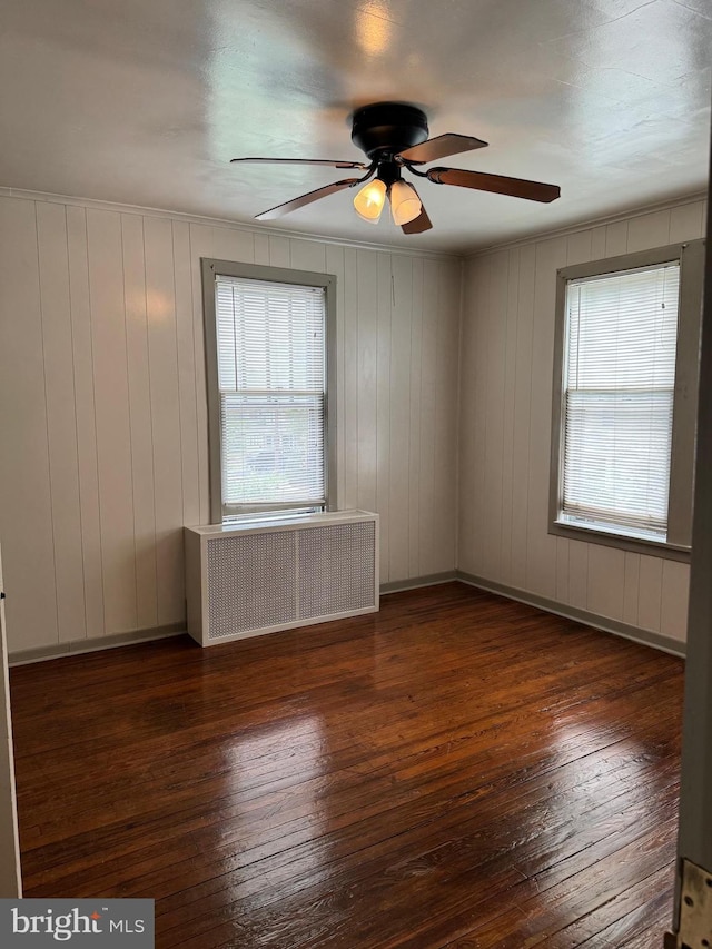 unfurnished room featuring ceiling fan, dark hardwood / wood-style floors, and radiator heating unit