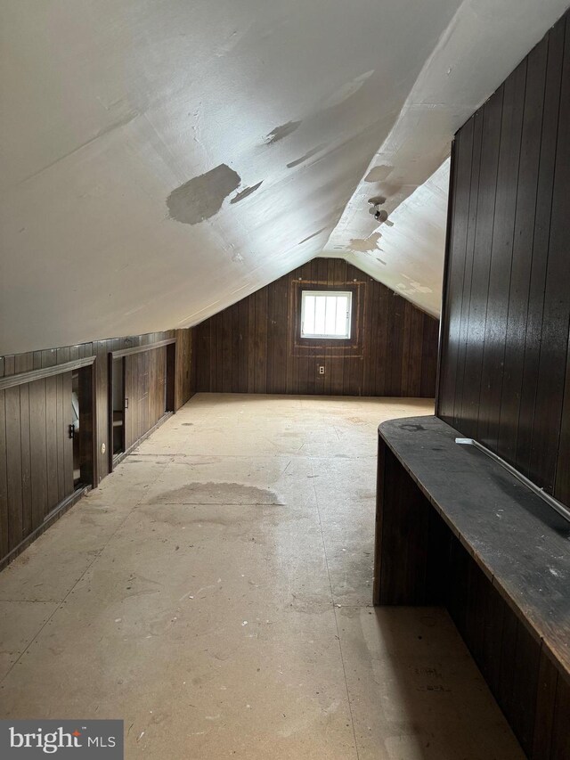 bonus room featuring lofted ceiling and wood walls