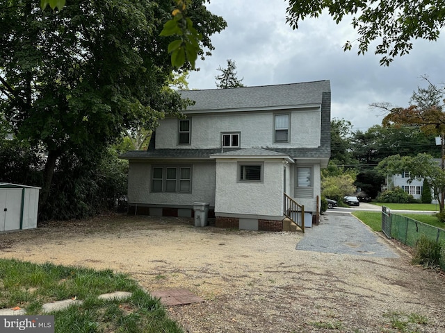 rear view of property with a storage shed