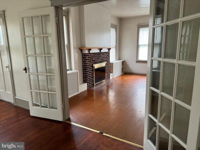 living room with dark wood-type flooring, wooden walls, and a fireplace