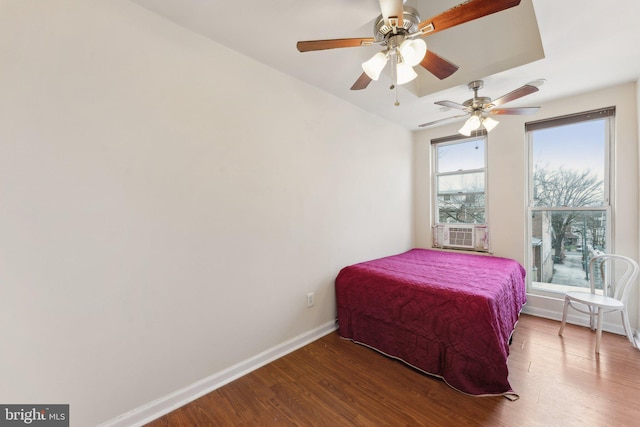 bedroom featuring ceiling fan, cooling unit, a raised ceiling, and wood-type flooring