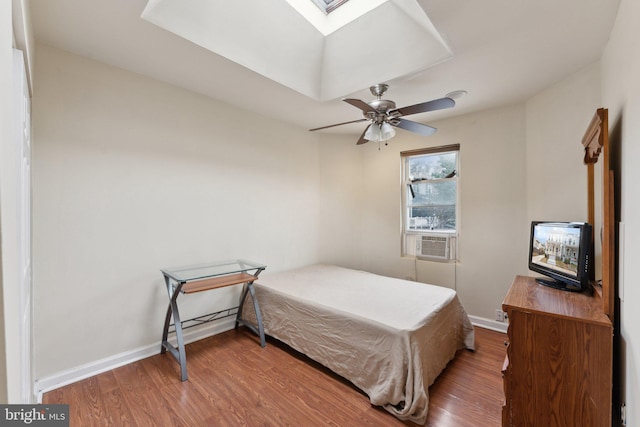 bedroom with a skylight, hardwood / wood-style flooring, ceiling fan, and cooling unit