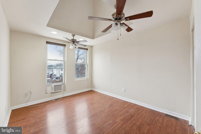 spare room with wood-type flooring, a raised ceiling, cooling unit, and ceiling fan