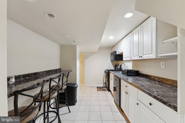 kitchen with black appliances, dark stone countertops, white cabinetry, and light tile patterned floors