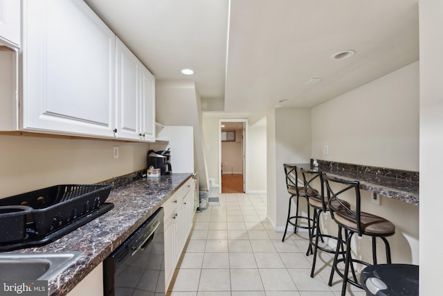 kitchen with a kitchen breakfast bar, light tile patterned floors, dark stone countertops, white cabinets, and black dishwasher